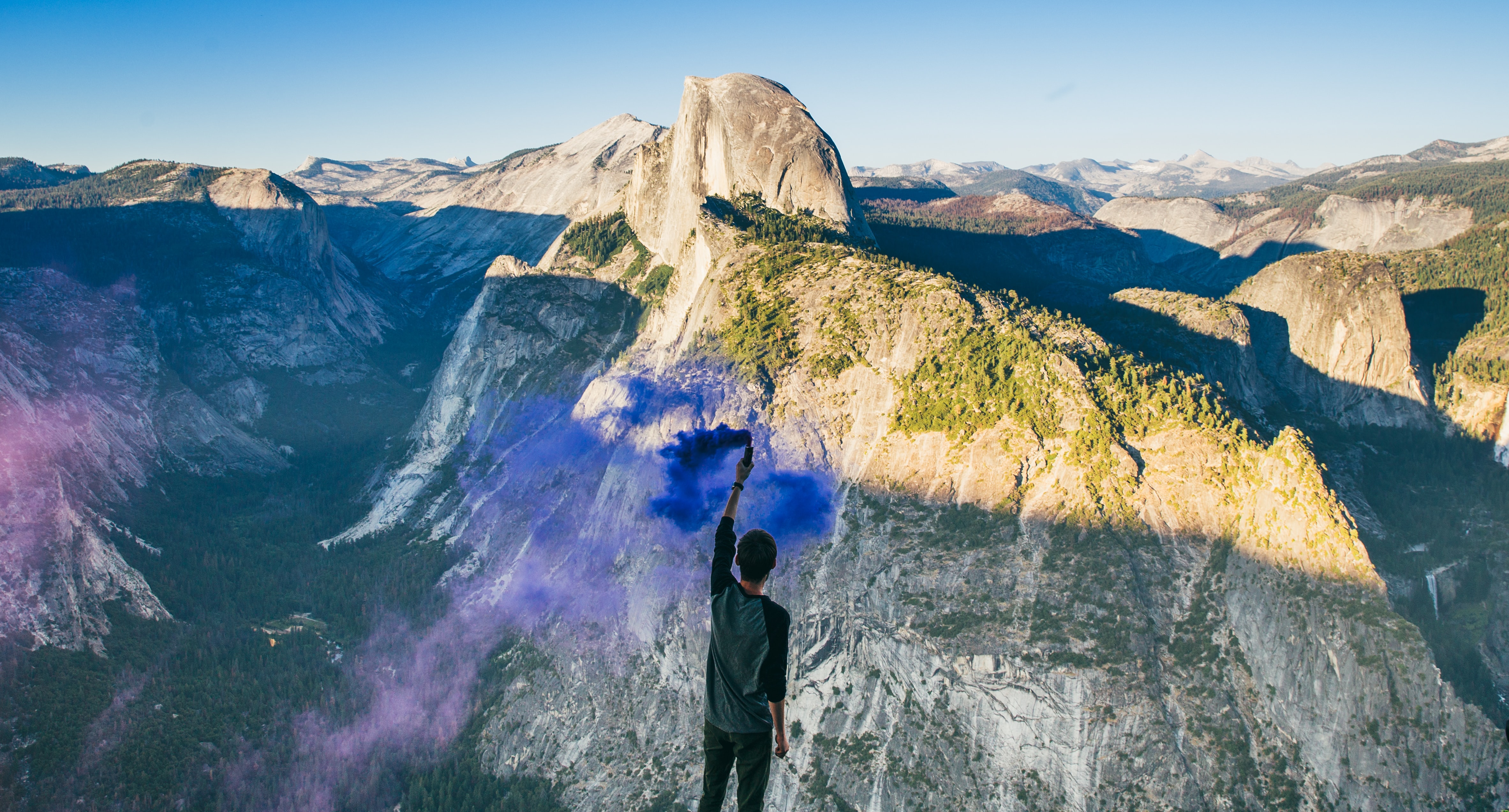 Man on mountain peak holding a smoke signal flair